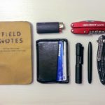 A small collection of items that can fit in a pocket, including Notes notebook, pen, Leatherman tool, lighter, and wallet